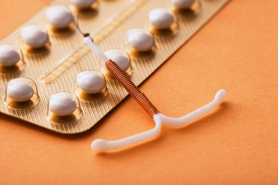 A copper IUD over top a sleeve of birth control pills.